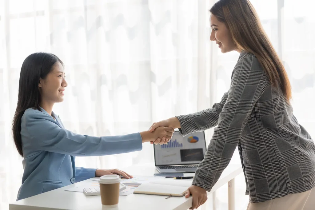 Two Asian businesswomen shake hands